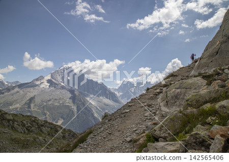 Hiker ascending rocky trail in mont blanc massif Hiker ascending rocky trail in mont blanc massif 142565406