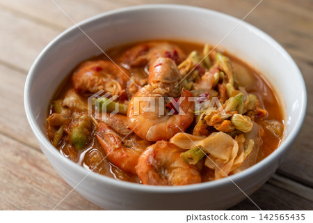 Traditional Thai sour curry whole shrimp mixed vegetables chili tamarind broth served hot white bowl wooden table Traditional Thai sour curry whole shrimp mixed vegetables chili tamarind broth served hot white bowl wooden table 142565435