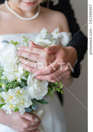 一張新娘和新郎擁抱的婚紗照,新娘手捧白色花束。 一張新娘和新郎擁抱的婚紗照,新娘手捧白色花束。 142566007