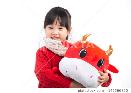 Smiling little girl hugging a red ox plush toy, celebrating the Year of the Ox, Chinese New Year theme. Smiling little girl hugging a red ox plush toy, celebrating the Year of the Ox, Chinese New Year theme. 142566520