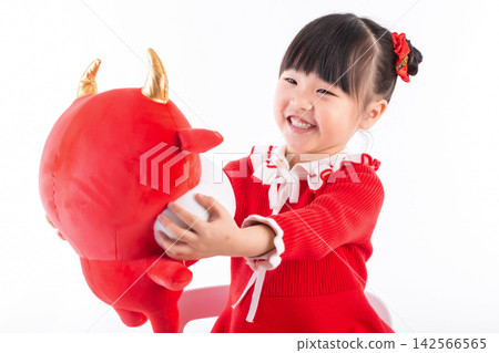 Smiling little girl hugging a red ox plush toy, celebrating the Year of the Ox, Chinese New Year theme. Smiling little girl hugging a red ox plush toy, celebrating the Year of the Ox, Chinese New Year theme. 142566565