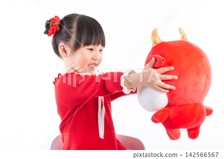 Smiling little girl hugging a red ox plush toy, celebrating the Year of the Ox, Chinese New Year theme. Smiling little girl hugging a red ox plush toy, celebrating the Year of the Ox, Chinese New Year theme. 142566567