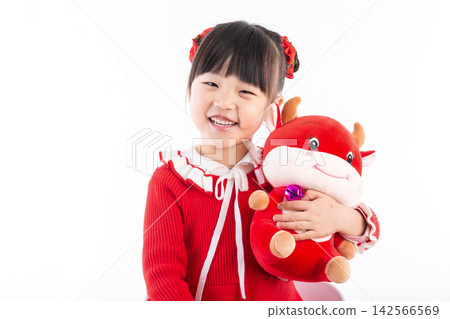 Smiling little girl hugging a red ox plush toy, celebrating the Year of the Ox, Chinese New Year theme. 142566569