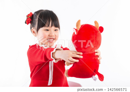 Smiling little girl hugging a red ox plush toy, celebrating the Year of the Ox, Chinese New Year theme. Smiling little girl hugging a red ox plush toy, celebrating the Year of the Ox, Chinese New Year theme. 142566571