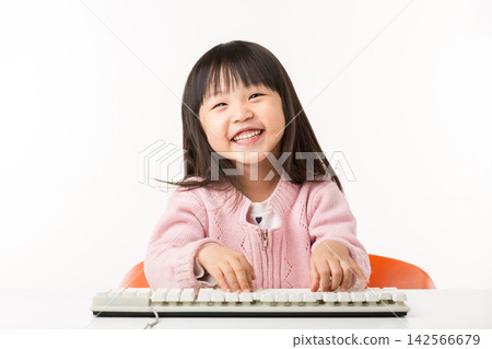 Happy Asian Little Girl Typing on Keyboard and Smiling Happy Asian Little Girl Typing on Keyboard and Smiling 142566679