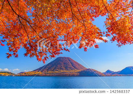 On a clear autumn morning, Mount Haruna and Lake Haruna, both covered in autumn foliage, can be seen from the Haruna Lake scenic road, through the autumn leaves in the upper part of the mountain. On a clear autumn morning, Mount Haruna and Lake Haruna, both covered in autumn foliage, can be seen from the Haruna Lake scenic road, through the autumn leaves in the upper part of the mountain. 142568337