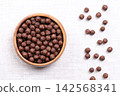 Choco balls, crispy breakfast cereal in a wooden bowl on linen, from above. Crispy corn food made of toasted cornmeal, cocoa powder, sweetened with sugar, enjoyed with milk, or eaten as a snack. Photo Choco balls, crispy breakfast cereal in a wooden bowl on linen, from above. Crispy corn food made of toasted cornmeal, cocoa powder, sweetened with sugar, enjoyed with milk, or eaten as a snack. Photo 142568341