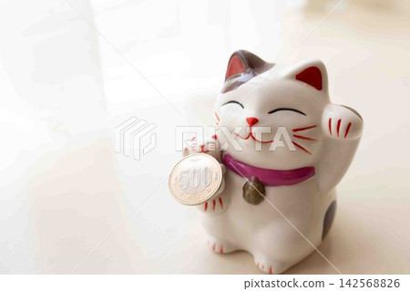 A lucky cat holding a 500 yen coin A lucky cat holding a 500 yen coin 142568826
