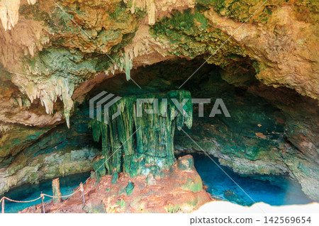 View of beautiful natural pool of crystal clear water formed in a rocky cave with stalagmites and stalagmites. Kuza cave in Zanzibar, Tanzania View of beautiful natural pool of crystal clear water formed in a rocky cave with stalagmites and stalagmites. Kuza cave in Zanzibar, Tanzania 142569654