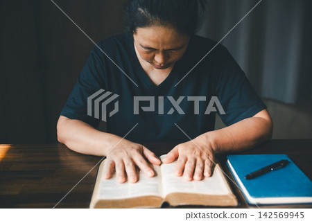 Adult person resting both hands on an open Bible beside a notebook and pen, representing scripture study, Christian faith, devotion, prayer, reflection, spiritual learning, guidance, Adult person resting both hands on an open Bible beside a notebook and pen, representing scripture study, Christian faith, devotion, prayer, reflection, spiritual learning, guidance, 142569945