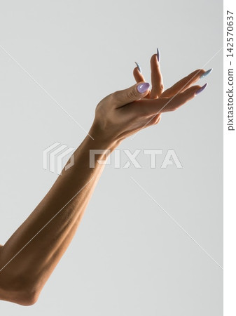 Woman's arm extended with elegant nails against a plain background Woman's arm extended with elegant nails against a plain background 142570637