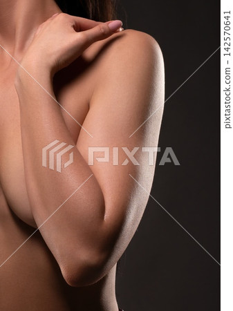 Close up of woman's arm across chest with hand on shoulder in studio Close up of woman's arm across chest with hand on shoulder in studio 142570641