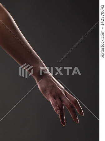 Arm and hand reaching down against a dark gray background Arm and hand reaching down against a dark gray background 142570642