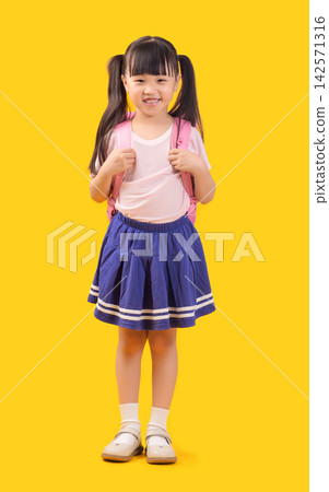 A cute Asian girl with a schoolbag on her back, a full-body portrait, stands in front of a yellow background in a photo studio. A cute Asian girl with a schoolbag on her back, a full-body portrait, stands in front of a yellow background in a photo studio. 142571316