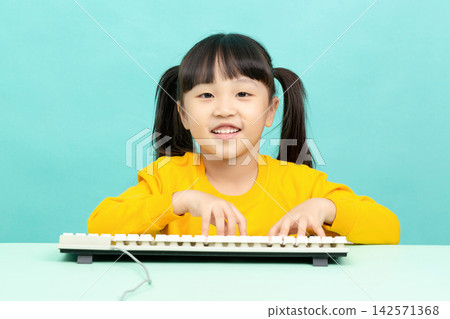 Cute Asian Little Girl Using Computer Keyboard and Smiling at Camera in Studio Background 142571368