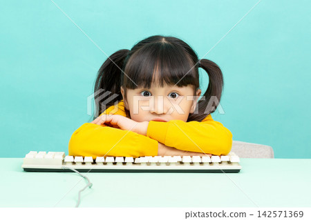 Smart young girl leaning on a computer keyboard and looking at the camera with a subtle smile. Smart young girl leaning on a computer keyboard and looking at the camera with a subtle smile. 142571369