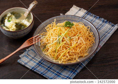 traditional Chinese cold noodles with scallion oil and shredded cucumber in a blue floral bowl 142572000
