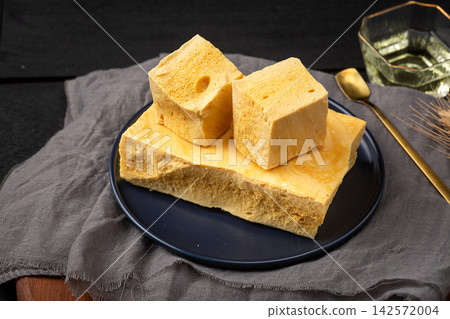 Handmade crispy honeycomb candy blocks on a black ceramic plate 142572004
