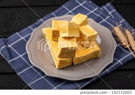 Bite sized pieces of handmade honeycomb sponge candy on a grey plate Bite sized pieces of handmade honeycomb sponge candy on a grey plate 142572005