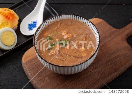 traditional Chinese millet porridge Doumo, authentic Henan breakfast savory soup with peanuts, eggs and side dishes on wooden table. traditional Chinese millet porridge Doumo, authentic Henan breakfast savory soup with peanuts, eggs and side dishes on wooden table. 142572008