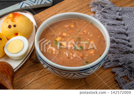 traditional Chinese millet porridge Doumo, authentic Henan breakfast savory soup with peanuts, eggs and side dishes on wooden table. traditional Chinese millet porridge Doumo, authentic Henan breakfast savory soup with peanuts, eggs and side dishes on wooden table. 142572009
