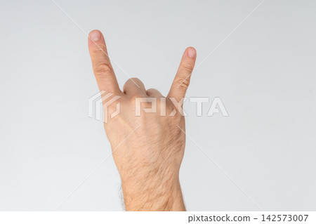 Male hand making the rock and roll devil horns gesture, symbolizing heavy metal music, energy, excitement and rebellious attitude with fingers extended against white background Male hand making the rock and roll devil horns gesture, symbolizing heavy metal music, energy, excitement and rebellious attitude with fingers extended against white background 142573007
