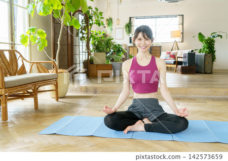 一位年輕的日本女性在客廳做瑜伽 一位年輕的日本女性在客廳做瑜伽 142573659