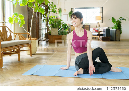 一位年輕的日本女性在客廳做瑜伽 一位年輕的日本女性在客廳做瑜伽 142573660