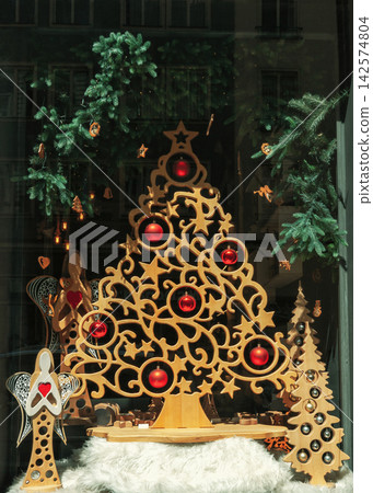 Decorative wooden Christmas tree with red baubles and angels in toy shop window Decorative wooden Christmas tree with red baubles and angels in toy shop window 142574804