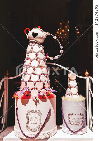 Sweet french macarons cookies cone with teapot on top, decorating showcase for pastry shop Sweet french macarons cookies cone with teapot on top, decorating showcase for pastry shop 142574805