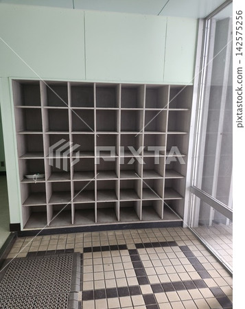 學校入口大廳有一個老舊空置的木製鞋架。 142575256