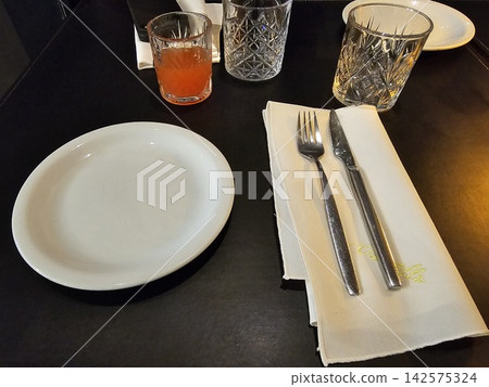 Cafe Table Setting with Plates Cutlery Glasses and Orange Drink Cafe Table Setting with Plates Cutlery Glasses and Orange Drink 142575324