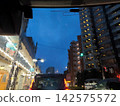 A view of the city skyline and the twilight blue sky from inside a car during a heavy rainstorm. 142575572