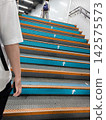 People going up the station stairs and arrow signs 142575573