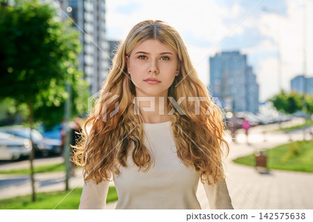 Serious blonde girl looking at camera on city street Serious blonde girl looking at camera on city street 142575638