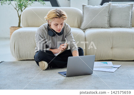 Young student studying with laptop on floor at home 142575659