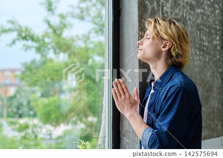 Peaceful teenage student praying with closed eyes Peaceful teenage student praying with closed eyes 142575694