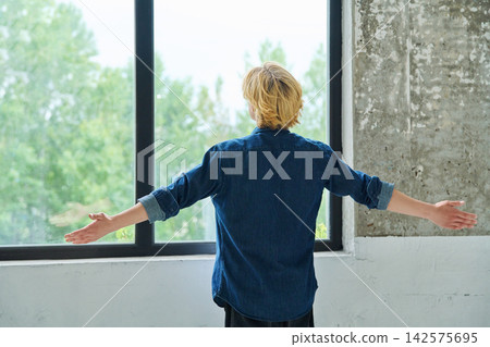 Young man standing back to camera with arms raised Young man standing back to camera with arms raised 142575695
