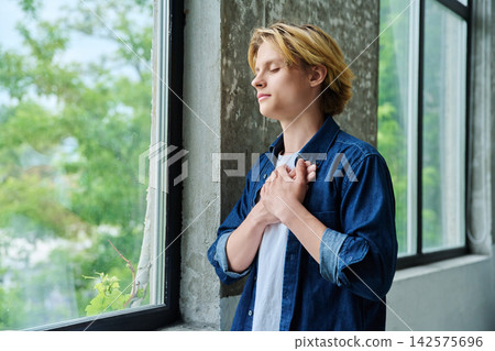 Peaceful young man with hands on chest closed eyes Peaceful young man with hands on chest closed eyes 142575696