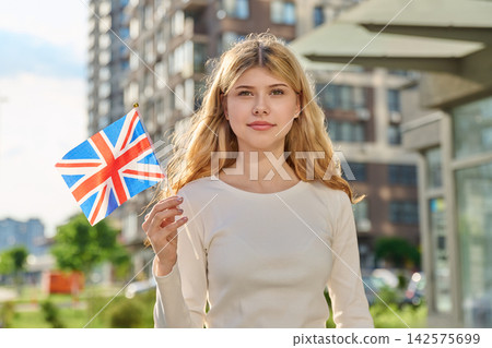 Happy girl holding British flag on sunny city street Happy girl holding British flag on sunny city street 142575699