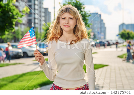 Happy blonde girl holding American flag in the city Happy blonde girl holding American flag in the city 142575701