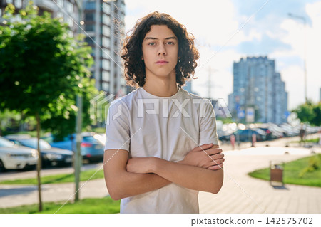 Serious teen boy with crossed arms on city street 142575702