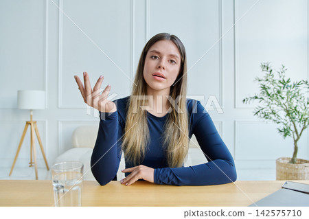 Concerned young woman looking directly at camera gesturing frustration during video call Concerned young woman looking directly at camera gesturing frustration during video call 142575710