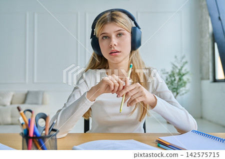 Teenage girl in headphones gesturing during video call 142575715