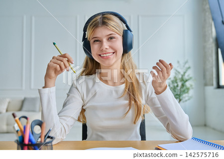 Happy female student in headphones learning at home Happy female student in headphones learning at home 142575716