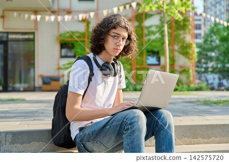 Teen student with laptop sitting on campus steps 142575720
