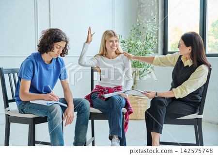 Psychologist supporting smiling teenage girl raising hand Psychologist supporting smiling teenage girl raising hand 142575748