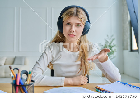 Teenage girl in headphones gesturing during video call Teenage girl in headphones gesturing during video call 142575750