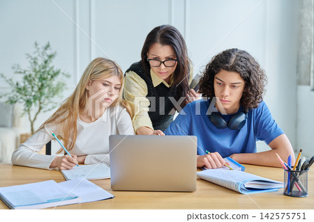 Two smiling teen students with laptop at desk 142575751
