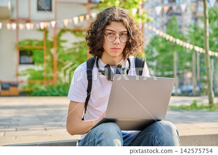 Teen student with laptop sitting on campus steps Teen student with laptop sitting on campus steps 142575754